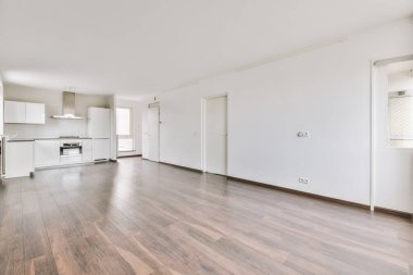 Pencereleri ve ahşap parke zemini olan boş beyaz mutfağın içi.