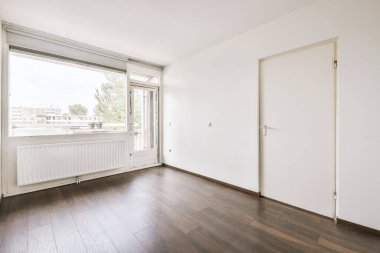 Evdeki boş ışık odasında, beyaz duvardaki plastik pencere ve radyatör.