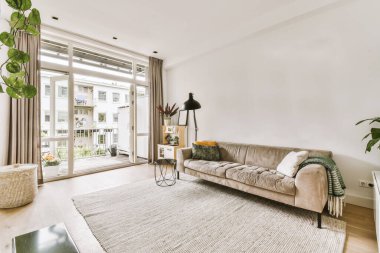 Mutfağın yakınındaki açık oturma odasında zarif avizenin altında yumuşak yastıklı büyük bir kanepe.