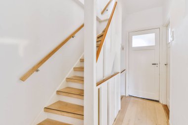 Beyaz spiral merdiven, çağdaş evi ahşap zemin ve beyaz duvarlarla birbirine bağlıyor.