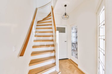 Beyaz spiral merdiven, çağdaş evi ahşap zemin ve beyaz duvarlarla birbirine bağlıyor.