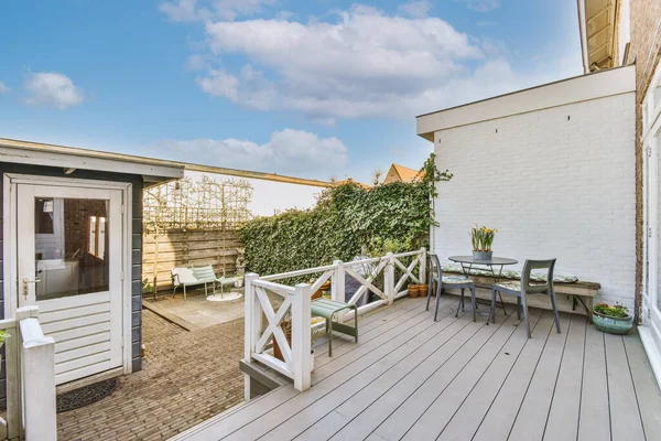 Neat paved patio with sitting area and small garden near wooden fence