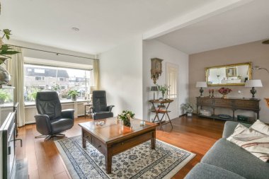 Çağdaş dairenin pencerelerine karşı rahat kanepesi ve televizyonu olan oturma odası.