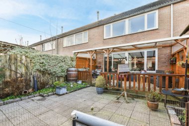 Oturma alanı ve ahşap çitlerin yanındaki küçük bahçesi olan düzgün asfaltlı bir avlu.