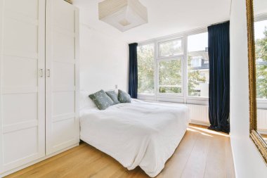 Yatak odasının iç tasarımı, yatak odası ve ahşap gardırop modern dairenin penceresinin kenarına yerleştirilmiş.