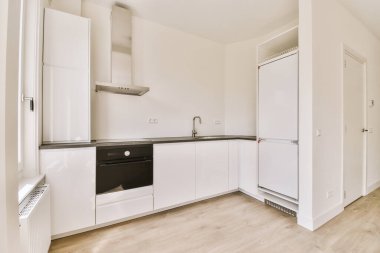 Minimalist tarzı beyaz mobilyalı, lavabolu ve sobalı bir ev mutfağı.