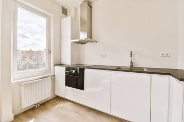 Minimalist tarzı beyaz mobilyalı, lavabolu ve sobalı bir ev mutfağı.