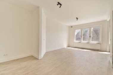 Evdeki boş ışık odasında, beyaz duvardaki plastik pencere ve radyatör.