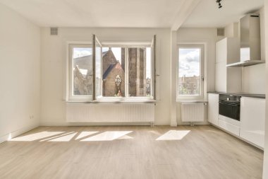 Pencereleri ve ahşap parke zemini olan boş beyaz mutfağın içi.