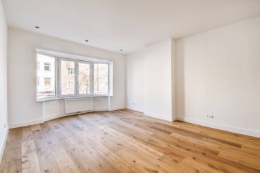 Evdeki boş ışık odasında, beyaz duvardaki plastik pencere ve radyatör.