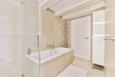 Aynalı lavabo ve temiz küvet modern banyoda cam kapılı ve beyaz fayanslı duvarları olan duş kutusunun yanında.