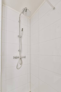 Duş muslukları cam bölmenin yanındaki fayanslı duvara bağlı ve evdeki tuvaletteki süs pervazı.