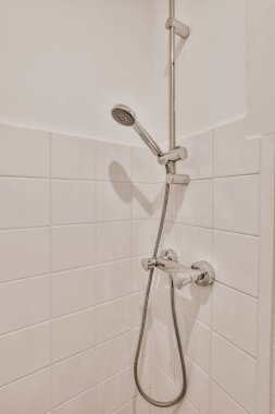 Evdeki modern tuvalette asılı duran banyo musluğu ile duvar arasındaki cam bölme.