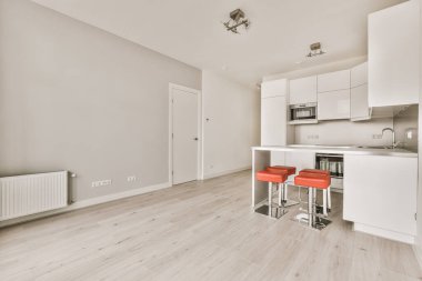 Pencereleri ve ahşap parke zemini olan boş beyaz mutfağın içi.