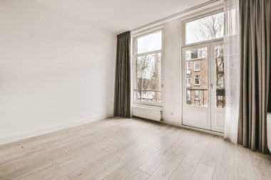 Pencereleri ve ahşap parke zemini olan boş beyaz mutfağın içi.