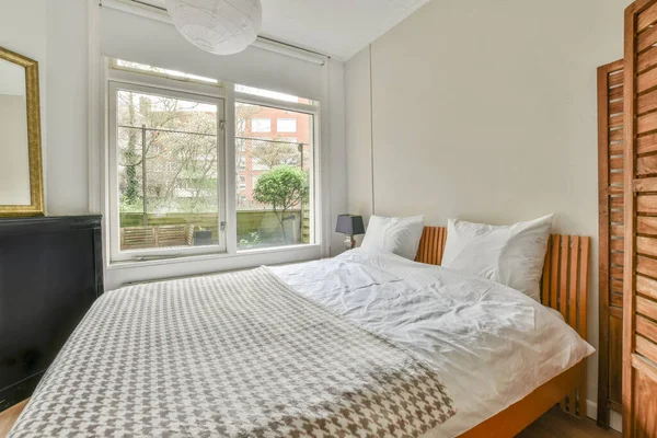 Comfortable bed and dining table in spacious bedroom with interior in minimal style