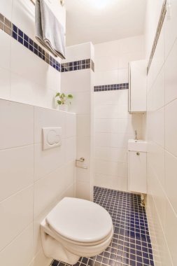 Lavabolu ve duvarlı, beyaz duvarlı ve kareli tuvaletli dar bir tuvalet.