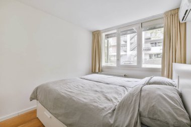 Yatak odasının iç tasarımı, yatak odası ve ahşap gardırop modern dairenin penceresinin kenarına yerleştirilmiş.