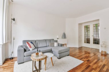 Modern apartmandaki dekorasyonlu ve televizyonlu, rahat koltuğun yanına yerleştirilmiş eski püskü ahşap masa.