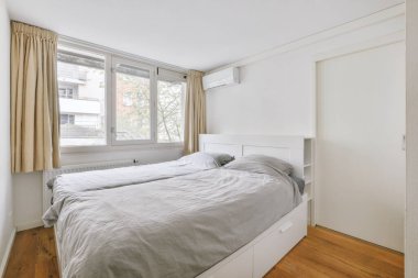 Yatak odasının iç tasarımı, yatak odası ve ahşap gardırop modern dairenin penceresinin kenarına yerleştirilmiş.