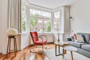 Modern apartmandaki dekorasyonlu ve televizyonlu, rahat koltuğun yanına yerleştirilmiş eski püskü ahşap masa.