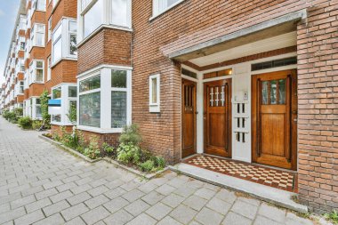 Levhalı, kaldırımlı ve ahşap kapılı bir binanın ön manzarası daireye çıkıyor.