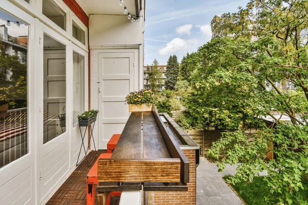 Narrow brick balcony with metal railings, wooden chair and door