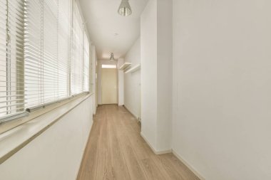 Beyaz duvarları ve aynalı gardırobu ve minimalist tarzda parke zemini olan boş dar koridor manzarası.