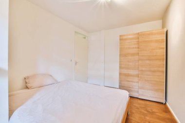 Cam kapının yanına konforlu battaniyeli rahat bir yatak ve hafif yatak odasındaki gardırop.