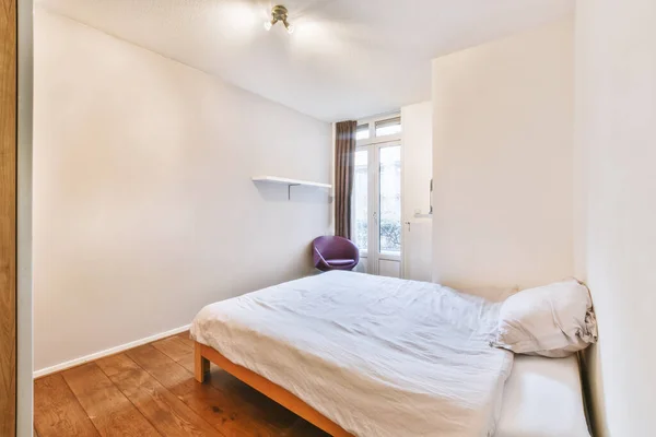 明るいベッドルームでガラスドアとワードローブの近くに配置された装飾的な毛布付きの快適なベッド — ストック写真