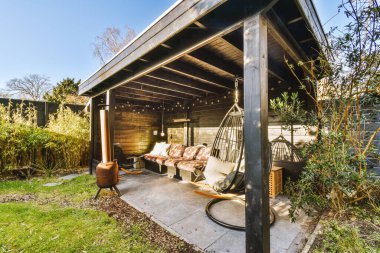 Neat paved patio with sitting area and small garden near wooden fence