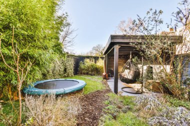 Neat paved patio with sitting area and small garden near wooden fence