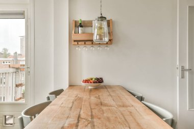 Stüdyo dairesinin modern minimalist tarzı iç tasarımı açık beyaz mutfak ve yemek masası ve sandalyeleri tavan arası lambasıyla aydınlatılmış.