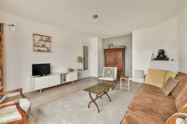 Modern apartmandaki geniş minimalist tarzda oturma odasında halı ve masaya yakın rahat bir kanepe.