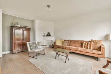 Modern apartmandaki geniş minimalist tarzda oturma odasında halı ve masaya yakın rahat bir kanepe.