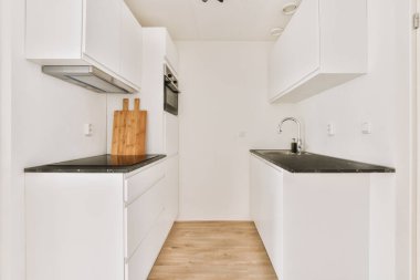 Minimalist tarzı beyaz mobilyalı, lavabolu ve sobalı bir ev mutfağı.