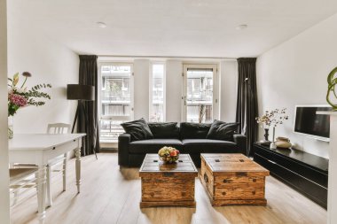 Modern apartmandaki dekorasyonlu ve televizyonlu, rahat koltuğun yanına yerleştirilmiş eski püskü ahşap masa.