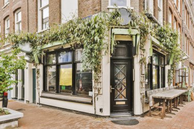 Levhalı, kaldırımlı ve ahşap kapılı bir binanın ön manzarası daireye çıkıyor.