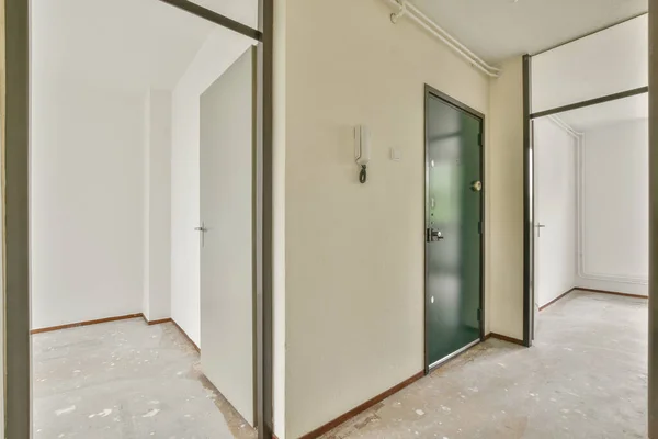 现代公寓有白色墙壁和门的狭窄走廊通向有窗户和地板的宽敞房间 — 图库照片