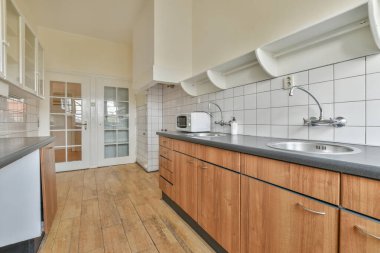 Pencereleri ve ahşap parke zemini olan boş beyaz mutfağın içi.