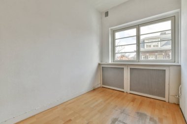 Evdeki boş ışık odasında, beyaz duvardaki plastik pencere ve radyatör.