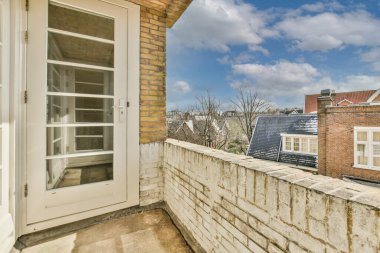 Büyük balkon pencereli, perdeli ve ahşap parke zeminli boş beyaz odanın içi.