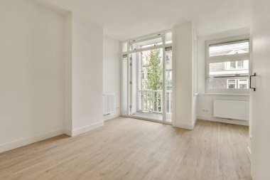 Büyük balkon pencereli, perdeli ve ahşap parke zeminli boş beyaz odanın içi.