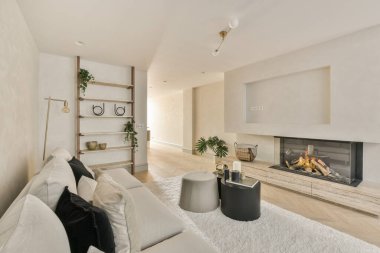 Oturma odasında renkli yastıklı büyük yumuşak kadife kanepe, ahşap parke ve kirişli mutfak adası.