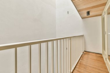 Duvara asılmış tuvalet ve köşedeki bej fayanslı lavabo.