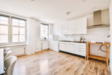 Günümüz minimalist tasarımı. Hafif stüdyo dairesinin ahşap masası ve oturma odası ile beyaz duvarları ve parke zemini arasında yemek masası ve sandalyeleri var.