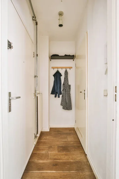 Corridor of contemporary apartment with black closets and doorway leading to terrace