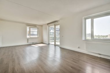 Giriş kapısı, beyaz duvarları ve parke zemini lambayla aydınlatılmış, geometrik tasarımı olan boş, modern bir daire.