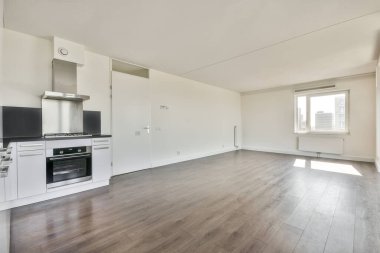 Pencereleri ve ahşap parke zemini olan boş beyaz mutfağın içi.