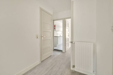 Koridoru ve ahşap parke zemini olan boş beyaz mutfağın içi.